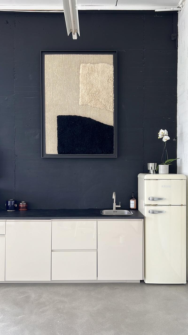 Modern kitchen with white cabinets, a stainless steel sink, a vintage-style refrigerator, and a dark grey wall with a framed artwork.