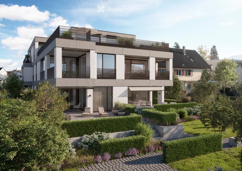 Modern two-story house with large windows, balconies, and a well-maintained garden with lounge chairs and potted plants.