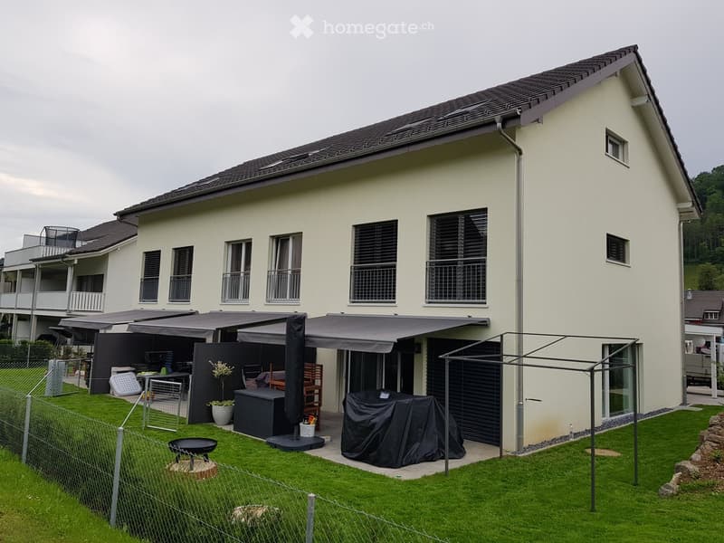 2 story house, beige exterior, black roof, large windows, awnings, garden, outdoor furniture, grill, potted plants