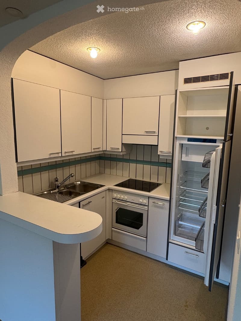 Modern kitchen with white cabinets, stainless steel appliances, and a built-in oven. Features a sink with a faucet, a refrigerator, and a countertop.