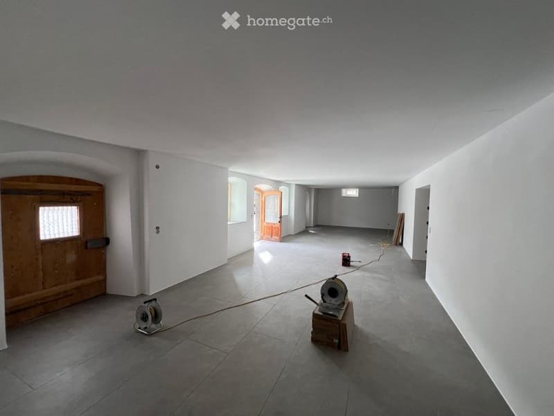 Empty room with bare walls, tiled floor, and a few construction tools and equipment placed on the floor.