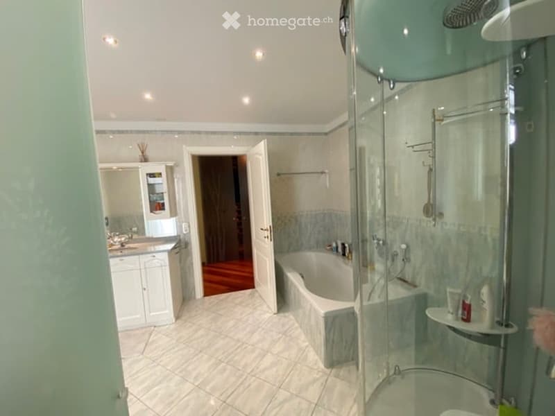 Modern bathroom with a bathtub, glass-enclosed shower, white tiled floor, and white cabinets.