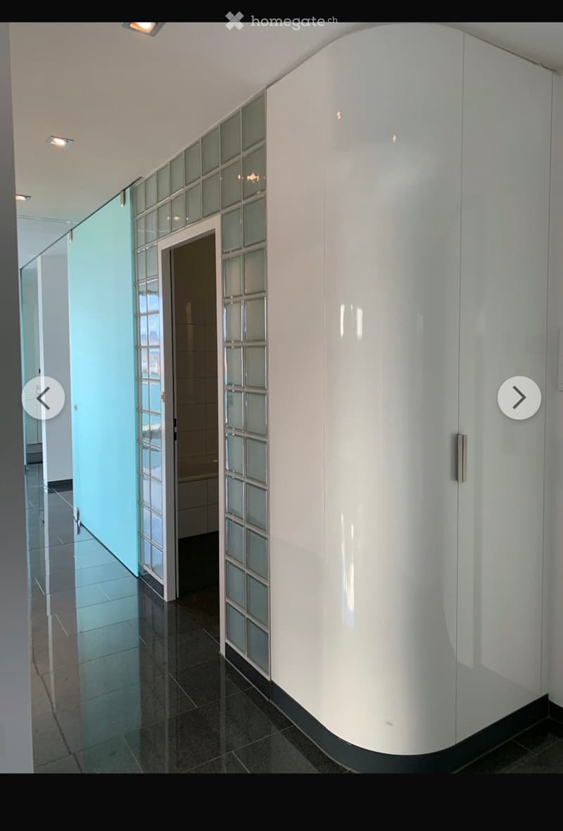Modern hallway with glass-paneled doors, white walls, and a polished tile floor.