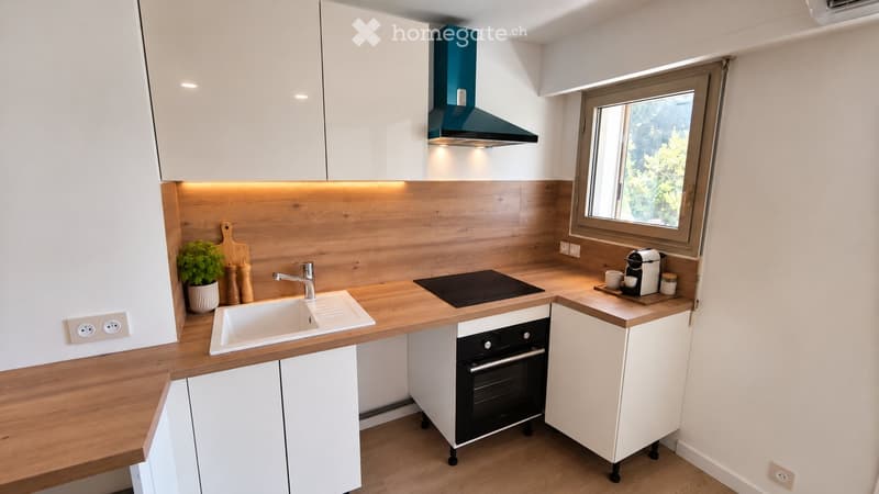 Modern kitchen with white cabinets, wooden countertops, built-in oven, sink, and coffee maker on the counter.
