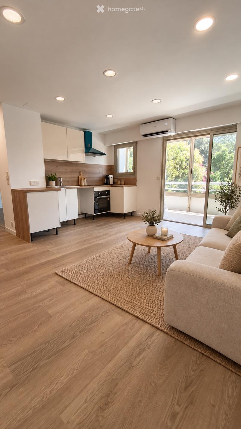 Modern open-plan living and dining area with a sofa, coffee table, and a small kitchen area featuring white cabinets, an oven, and a sink.