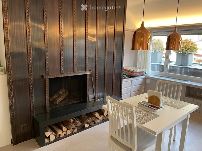Modern dining area with a fireplace, white dining table, chairs, and pendant lights.