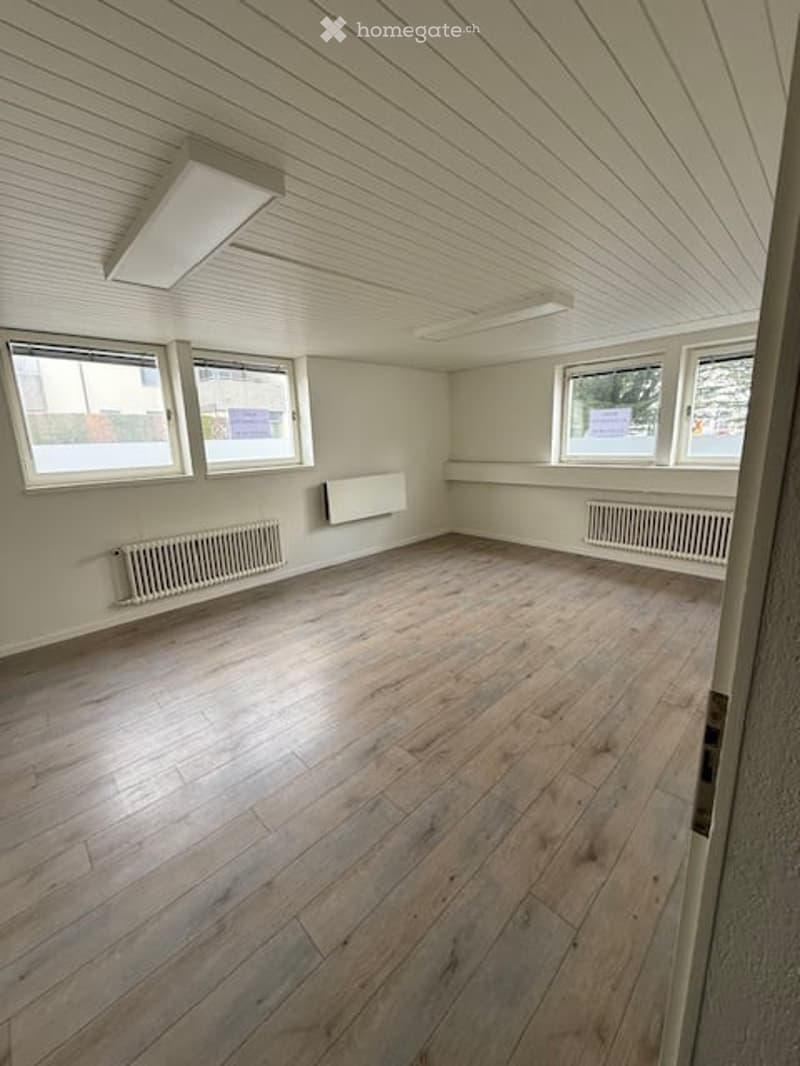 Empty room with wooden flooring, white walls, and large windows. No furniture or equipment present.