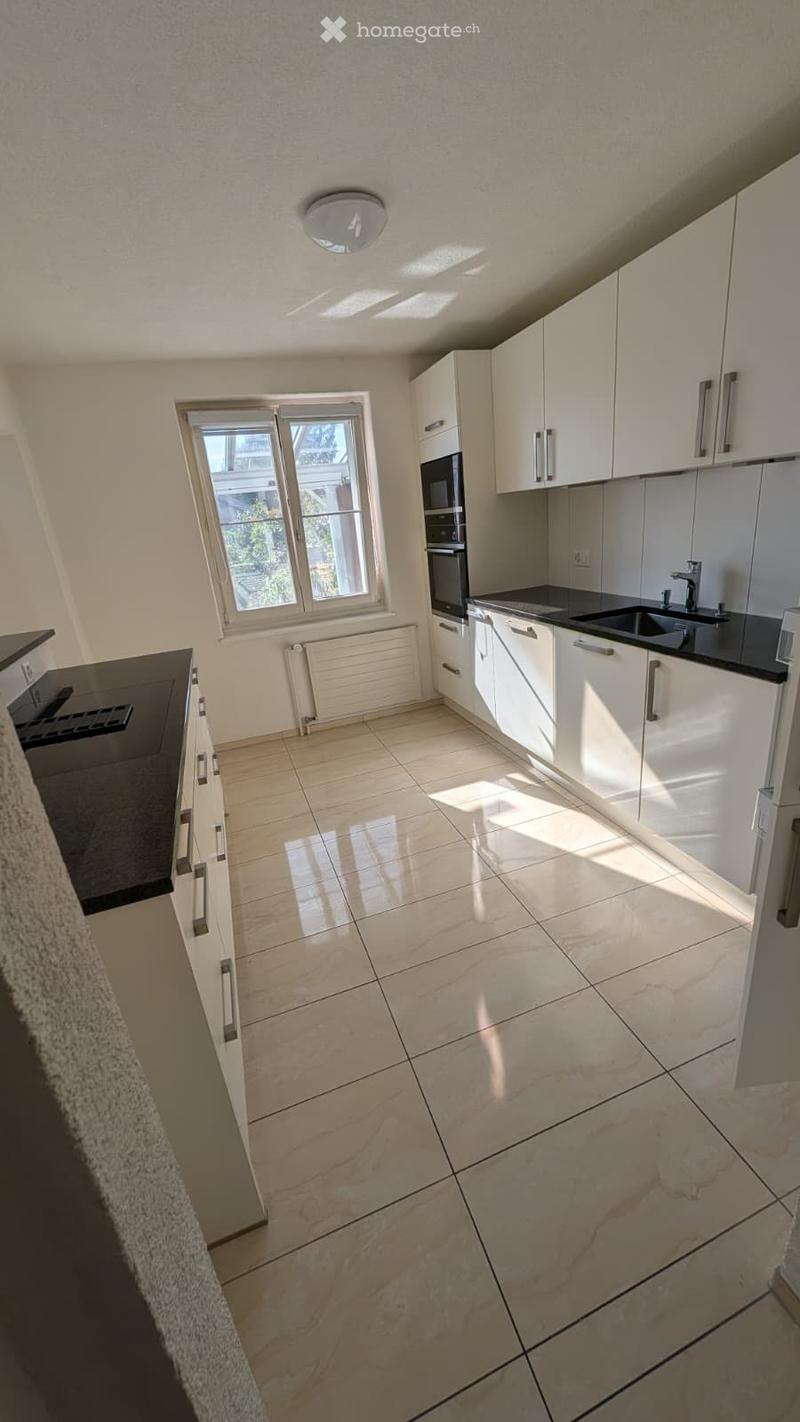 Modern kitchen with white cabinets, granite countertop, and tiled floor. Features a window, sink, oven, and microwave.