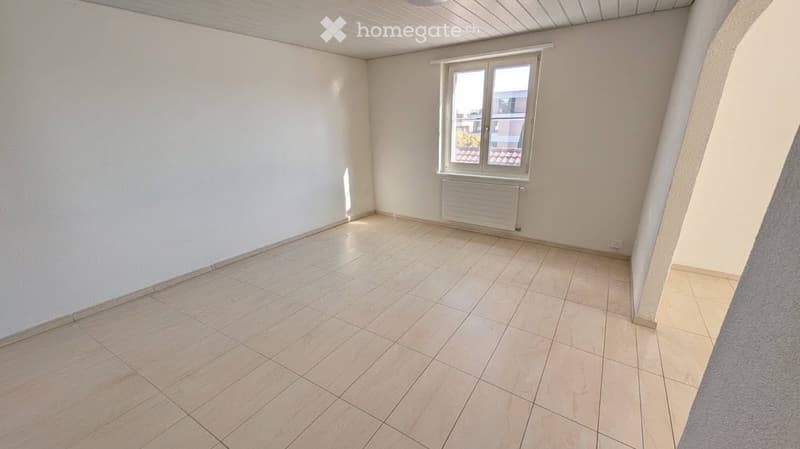 Empty room with tiled floor, white walls, and a single window with a radiator below it.