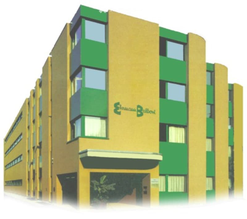 Modern multi-story building with yellow and green facade, large windows, and a sign reading "Sanjay Club Baldev".