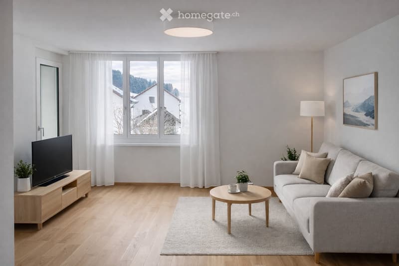 Modern living room with light wooden flooring, large windows with white curtains, a grey sofa with throw pillows, a round coffee table, a flat-screen TV on a wooden stand, and a floor lamp.