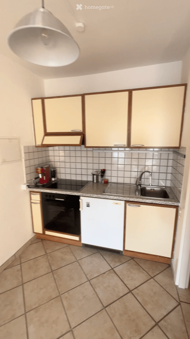 Modern kitchen with light-colored cabinets, tiled backsplash, granite countertop, and stainless steel sink and faucet.