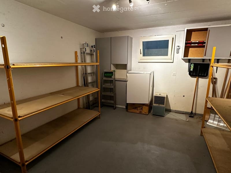 Empty room with exposed wooden shelving units, a small window, and basic storage cabinets. No furniture or personal items are present.