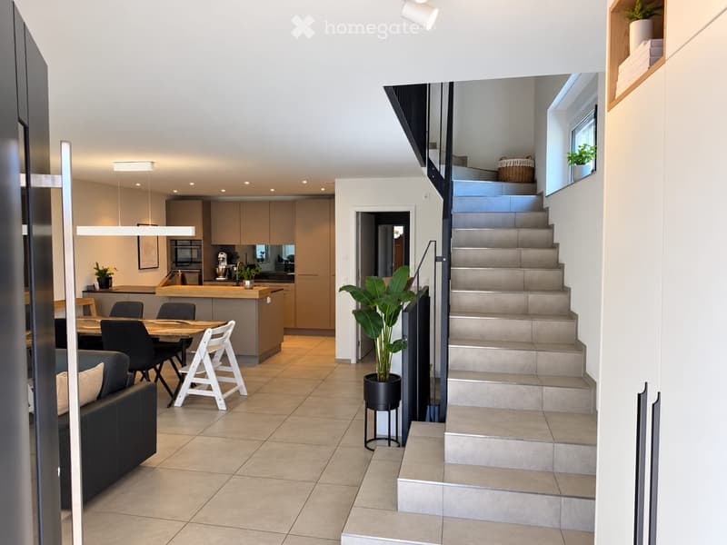 Open-plan living and dining area with modern kitchen, staircase leading to upper level, and contemporary furniture.
