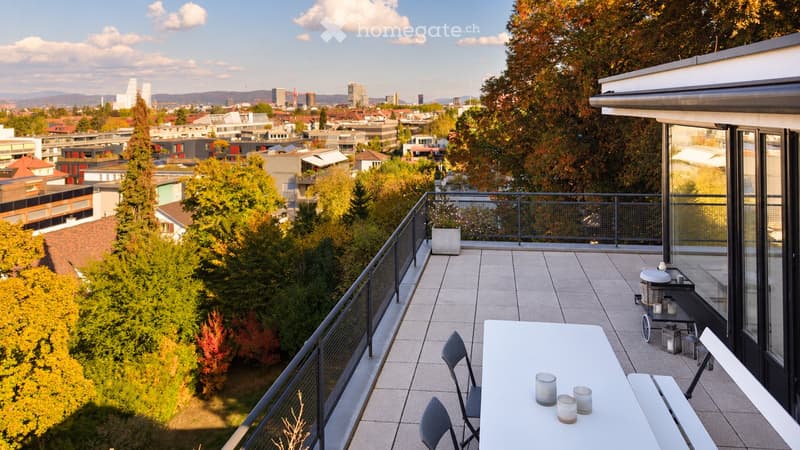 Balcony with a view of the city, featuring a white table, chairs, and candles.