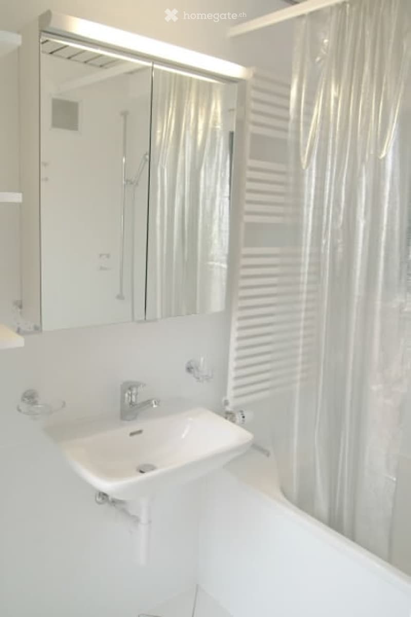 Modern bathroom with a white sink, mirror cabinet, and shower curtain.