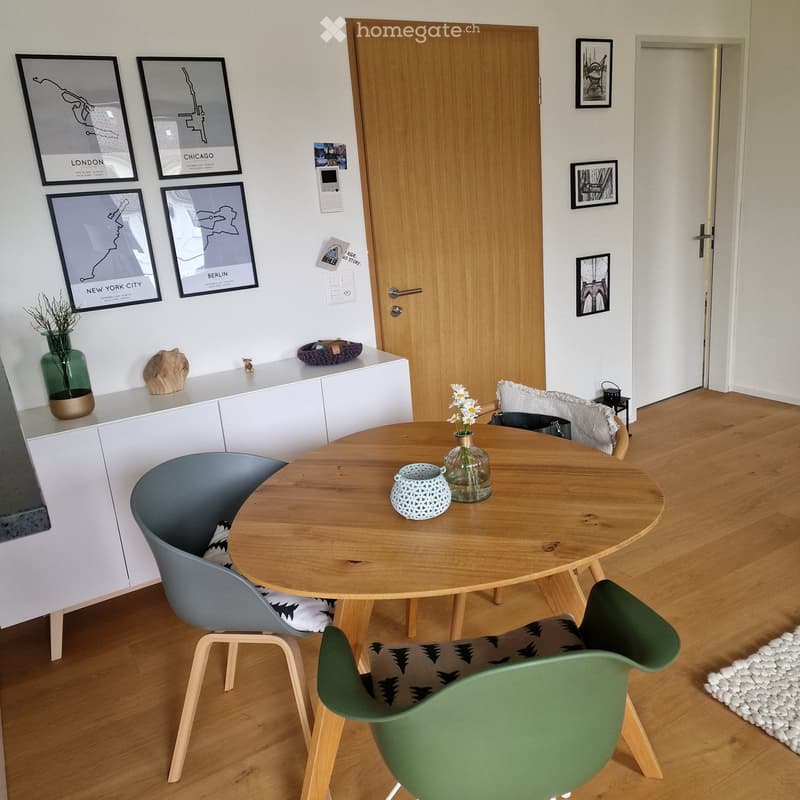Wooden dining table, 3 chairs, white cabinet, pictures on the wall, wooden floor