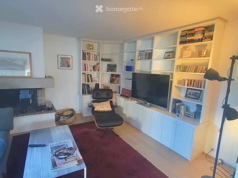 Modern living room with a fireplace, bookshelf, sofa, coffee table, and a comfortable chair.