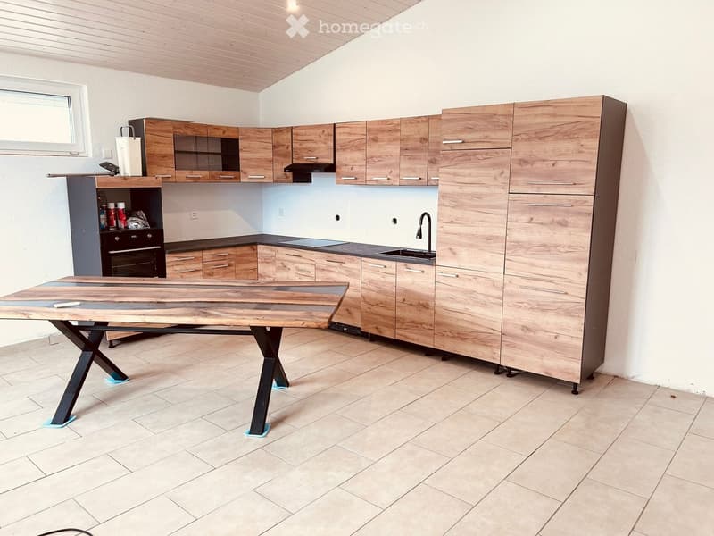 modern kitchen with wooden cabinetry, large dining table, tiled floor, black stove, under cabinet lighting, kitchen island, sink with faucet, open shelving, electrical outlets