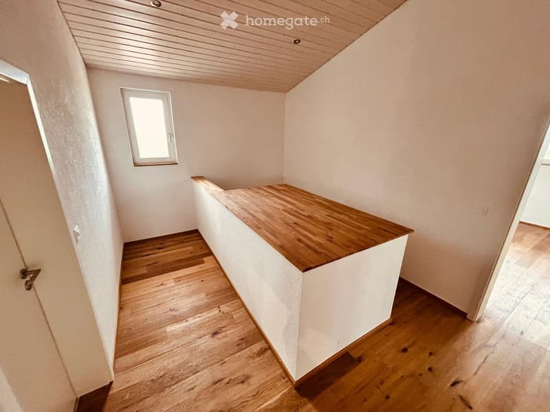 Staircase with wooden steps and handrail, white walls, small window, and a light fixture on the ceiling.