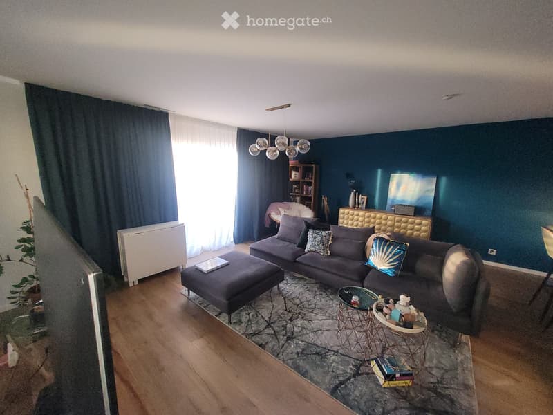 Modern living room with dark blue walls, a sectional sofa, ottoman, coffee table, side table, bookshelf, and artwork.