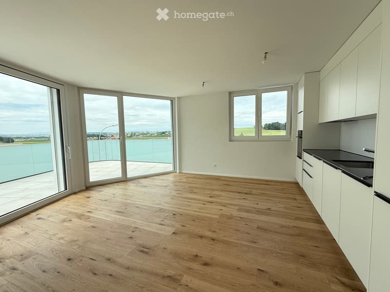 Living room with balcony, large windows, open sliding doors, hardwood floor, white walls, modern kitchen