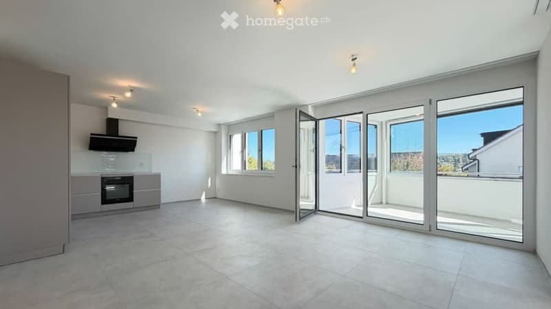 Empty room with white walls, tiled floor, large windows, and sliding glass doors leading to a balcony.