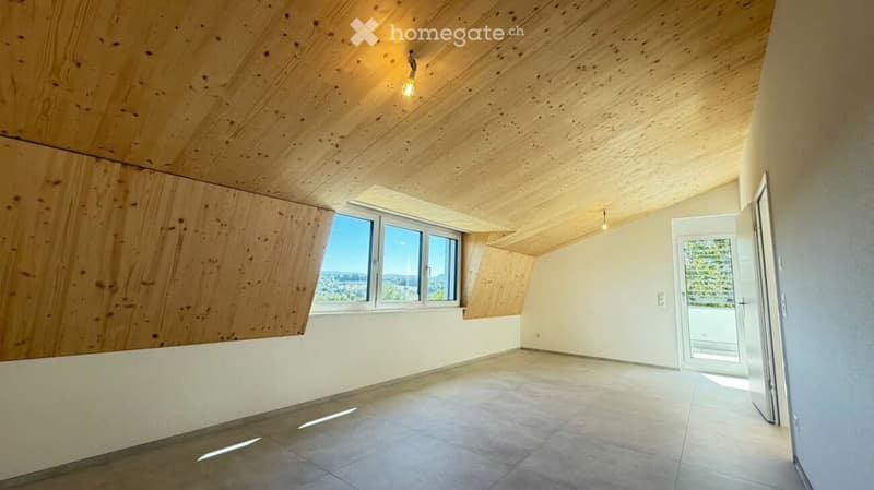 Empty room with wooden slatted ceiling, large window, and open doorway leading to outdoor area.