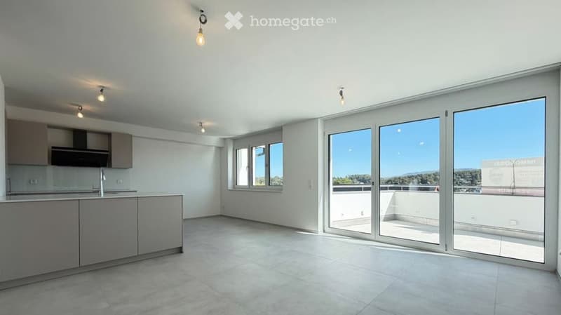 Modern, unfurnished kitchen with sleek grey cabinets, a central island, and large glass sliding doors leading to a balcony.