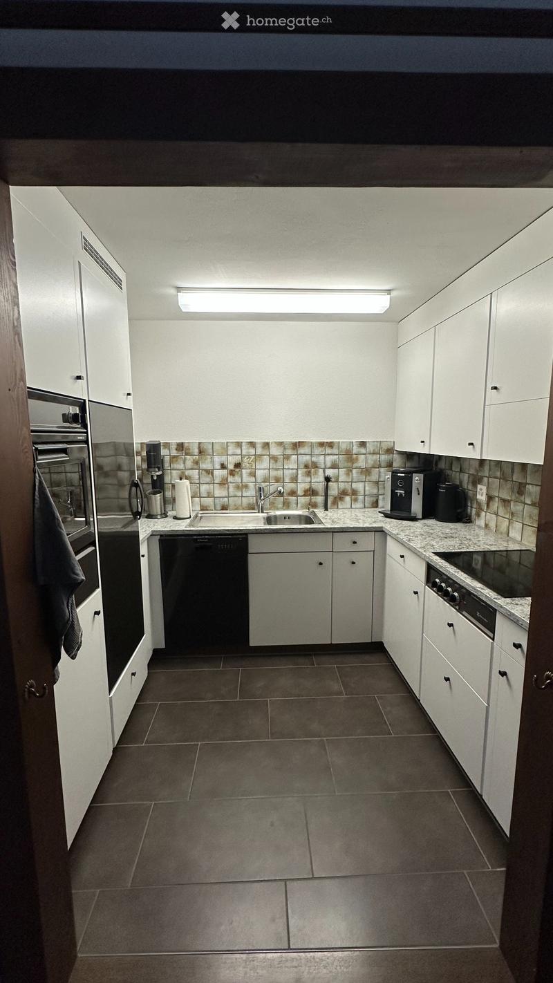 Modern kitchen with white cabinets, granite countertops, stainless steel appliances, and a tiled backsplash.