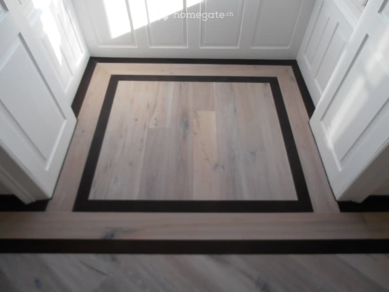 Raised ground floor with wooden flooring and white walls.