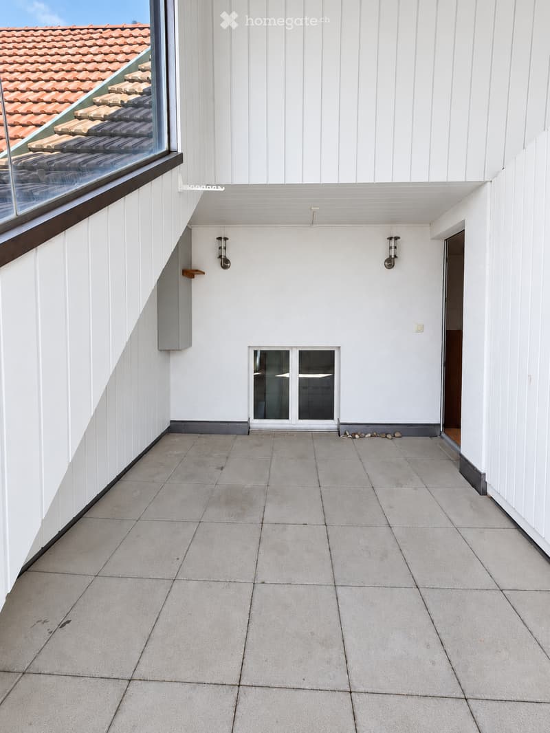 Modern balcony with white wooden paneling, tiled floor, large window overlooking a tiled roof, and a small window in the center.