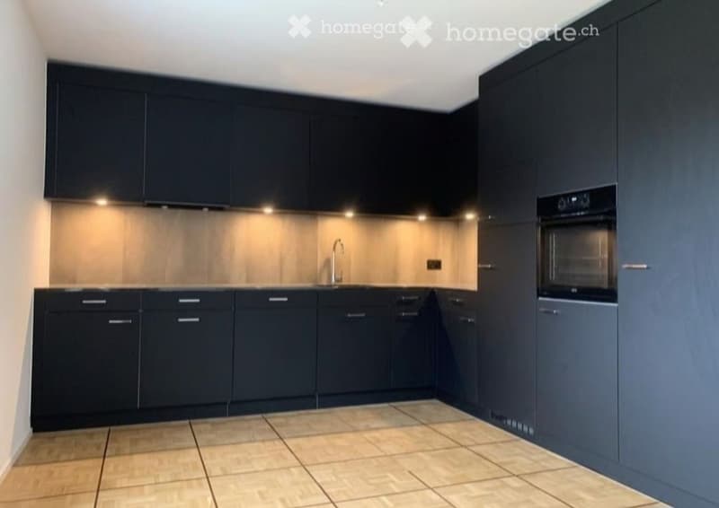 Modern kitchen with dark blue cabinets, a stainless steel faucet, and built-in oven.