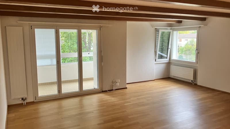 Empty room with wooden flooring, large sliding glass doors leading to a balcony, and white walls.