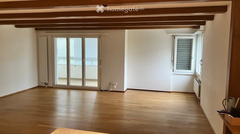 Empty room with wooden flooring, white walls, large sliding glass doors, and a window with blinds.