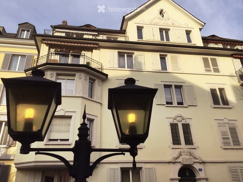 Classic European building with ornate facade, multiple windows with shutters, and a balcony on the upper floor.