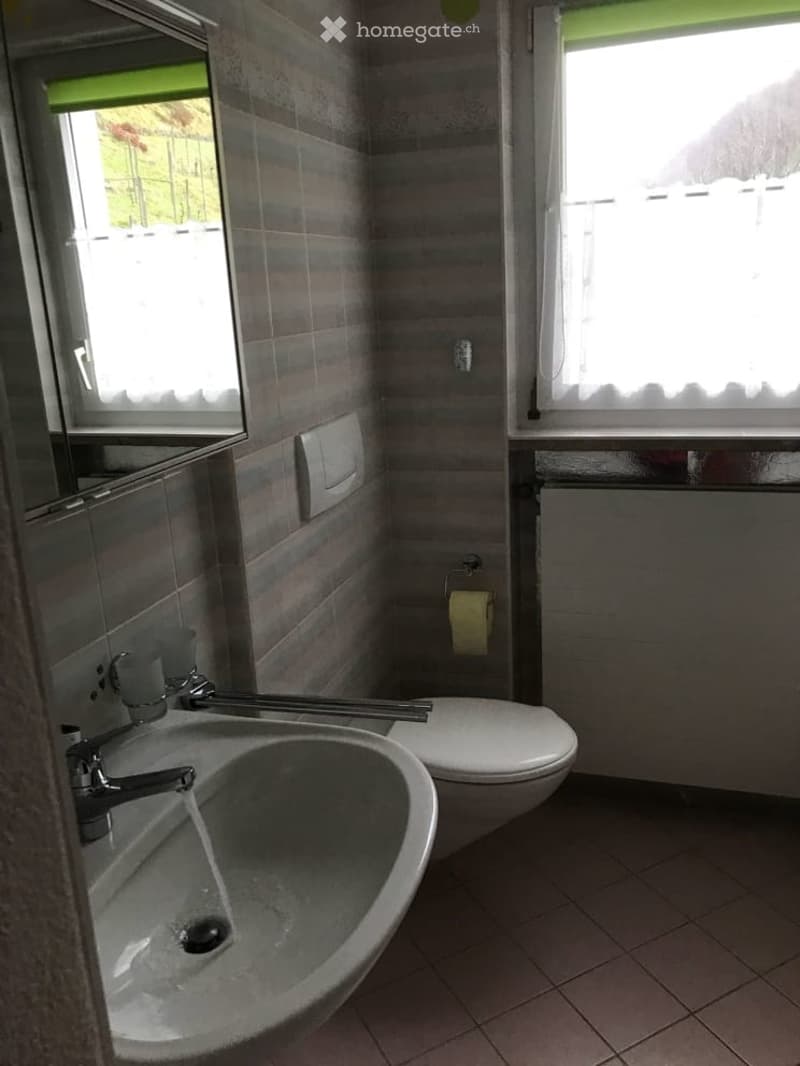 Bathroom with white tiles, sink, toilet, and mirror