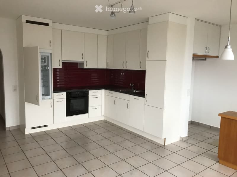 Modern kitchen with white cabinets, black countertop, modern oven, dishwasher, refrigerator with freezer, and tiled floor.