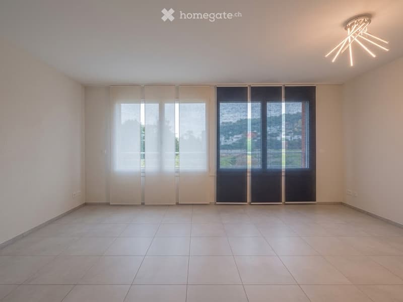 Empty room with tiled floor, large windows with blinds, and a modern ceiling light fixture.