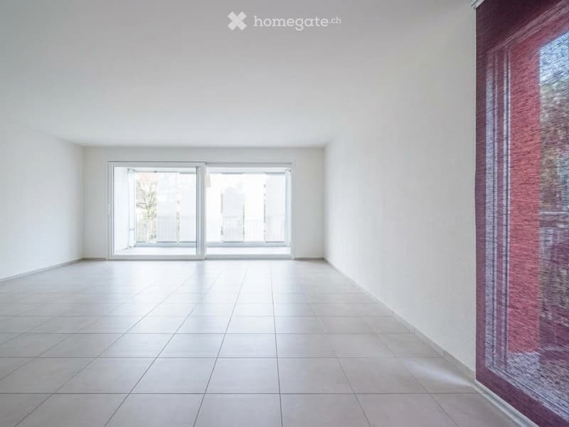 Empty room with white walls, tiled floor, and large sliding glass doors leading to a balcony.