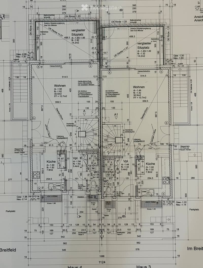 Floor plan of a multi-unit residential building showing two apartments (Wohnen), two kitchens, two bathrooms (WC), and a shared balcony area with seating.