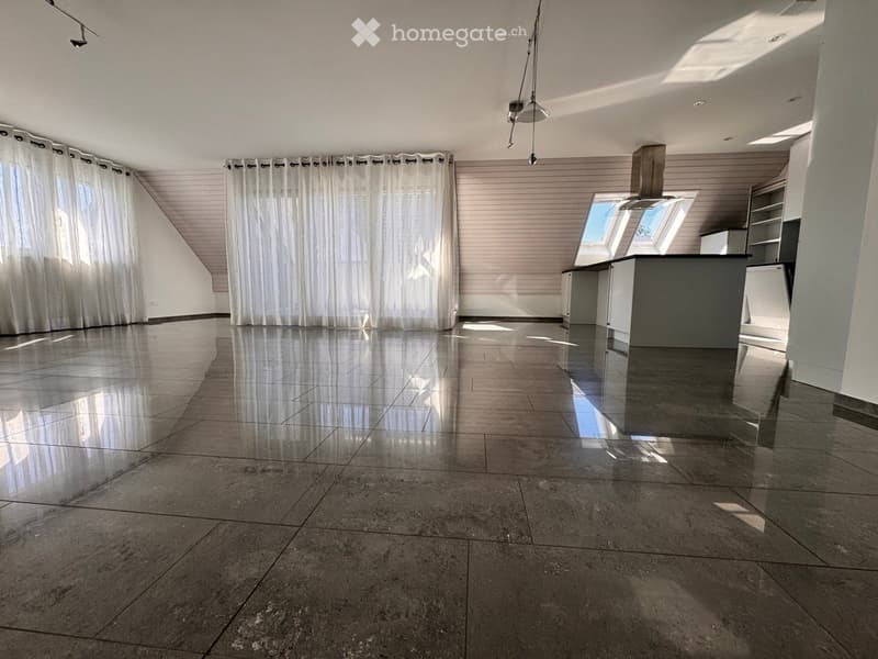 Empty room with polished tile flooring, white walls, and a modern kitchen area with cabinets and a countertop. Natural light streams in from large windows with white curtains.
