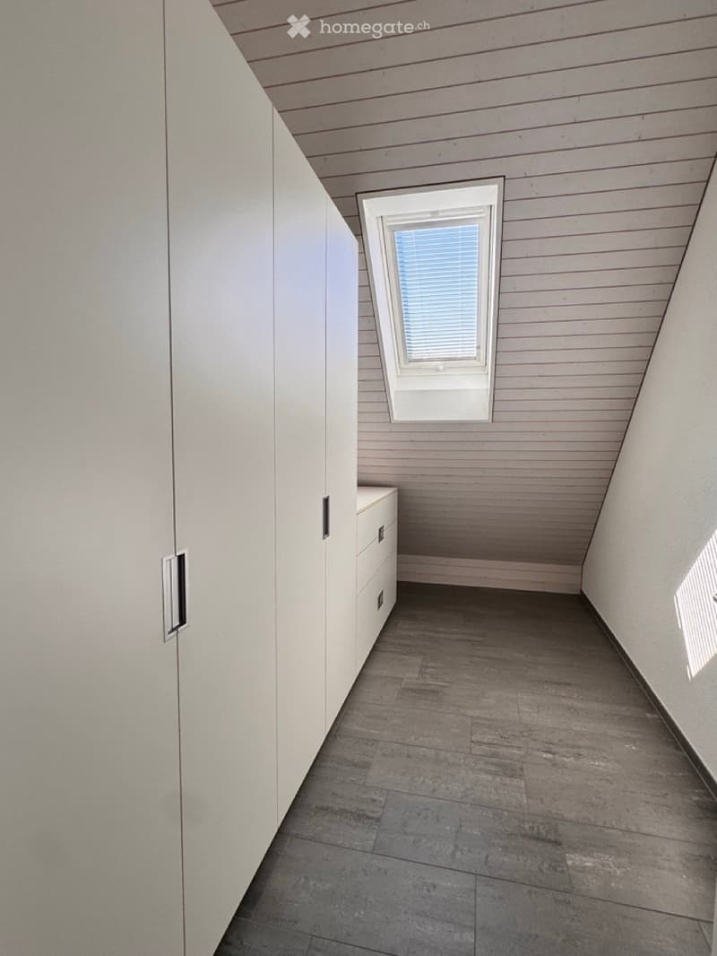 Empty room with wooden flooring, white walls, built-in closet, and a small window with blinds.
