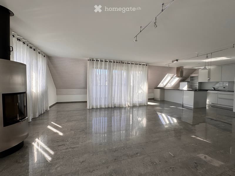 Open-plan living and kitchen area with a modern fireplace, sleek kitchen island, and large windows with curtains.