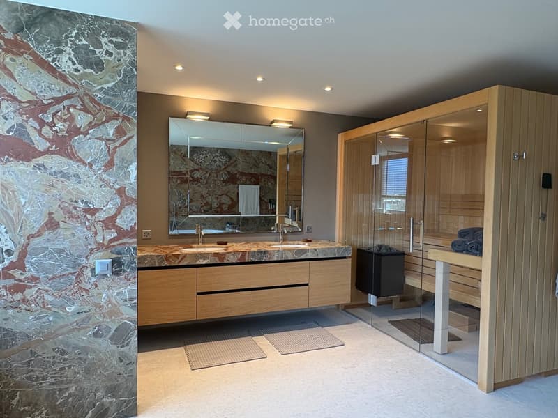 Modern bathroom with double sink vanity, large mirror, wooden cabinet, glass-enclosed sauna area, and marble accent wall.