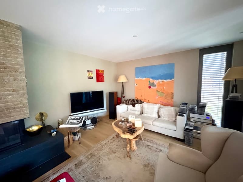 Modern living room with a white sofa, coffee table, television, floor lamp, speaker, and artwork on the walls.