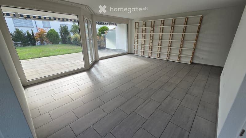 Empty room with tiled floor, large windows, and built-in shelving unit. No furniture or equipment present.