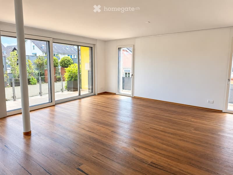 Empty room with wooden flooring, large sliding glass doors, and white walls.