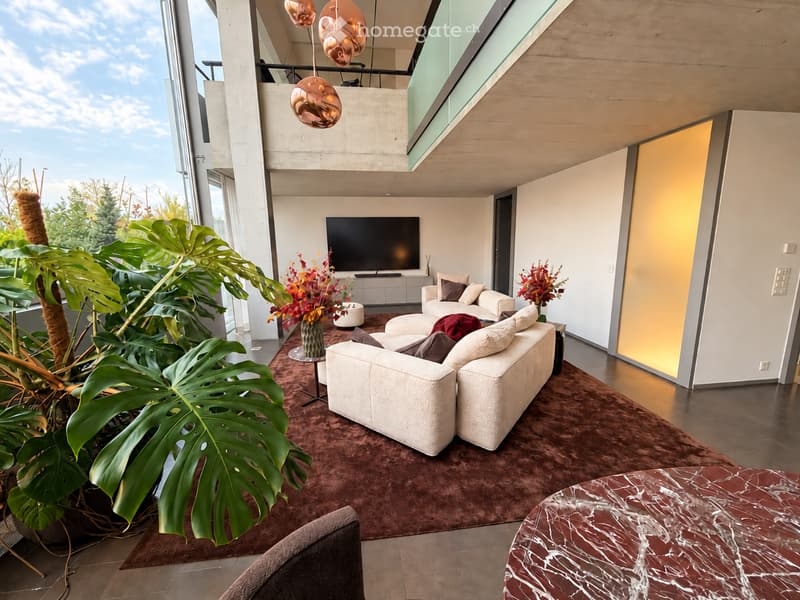 Modern living room with large windows, white sofa, coffee table, ottoman, armchair, marble side table, television, and decorative plants.
