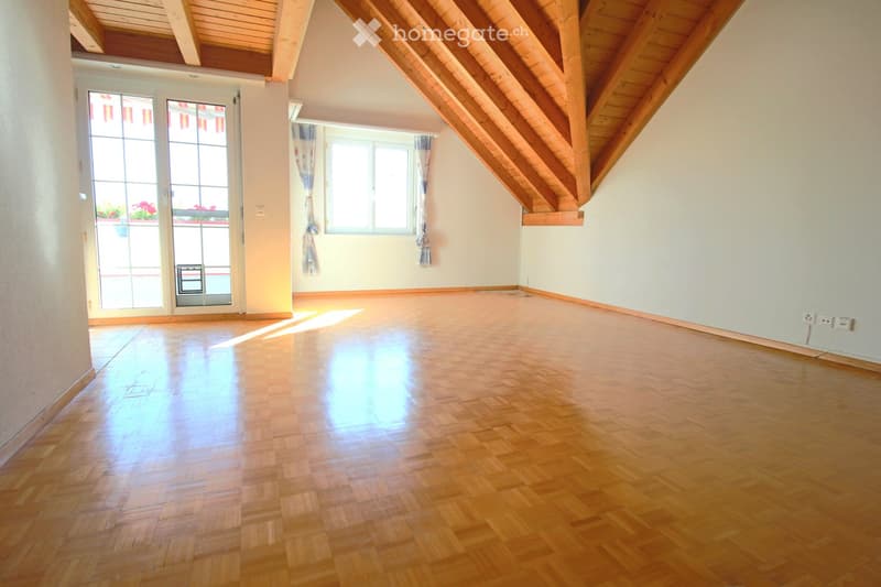 Empty room with wooden flooring, white walls, large windows, and a sliding glass door leading to a balcony.